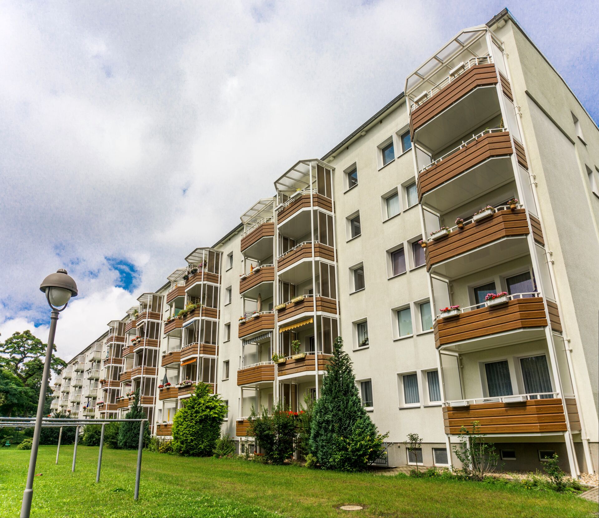 Schön gestalteter Wohnblock mit vielen Grünflächen und davor einer Laterne und Wäscheständer